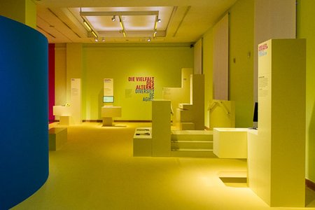 Photo of the Yellow Room in a Dialogue with Time exhibition with the stations to experience age-related limitations.