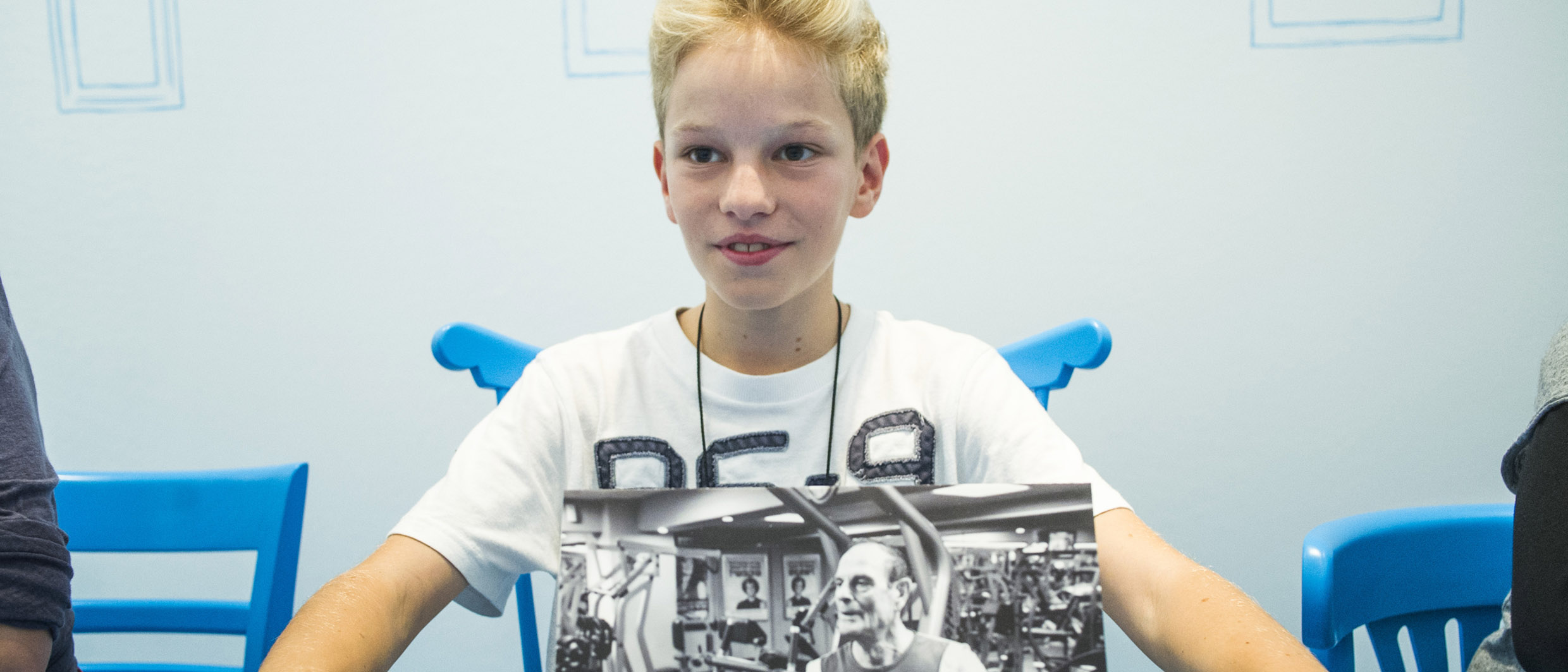 Foto eines Jungen, der im Dialograum der Dialog mit der Zeit-Ausstellung ein Bild zeigt, dass seine Vision eines Lebens im Alter symbolisiert.