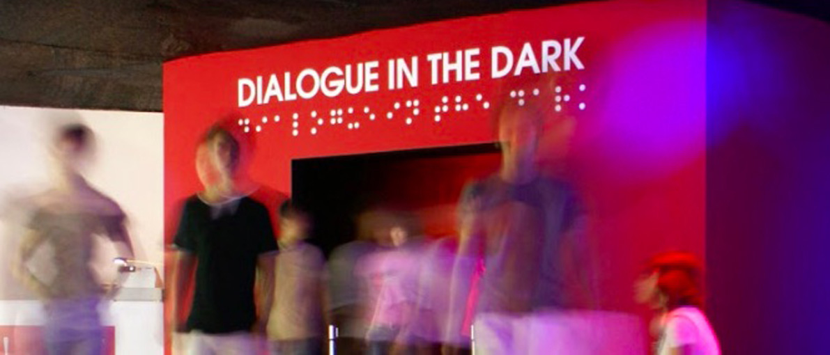 Bild eines Dialog im Dunkeln Ausstellungseingangs mit lachenden Besuchern
