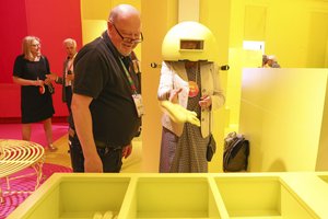 Dialogue with Time, Yellow Room - Photo of a guide helping a visitor with one of the "experience ageing" games.
