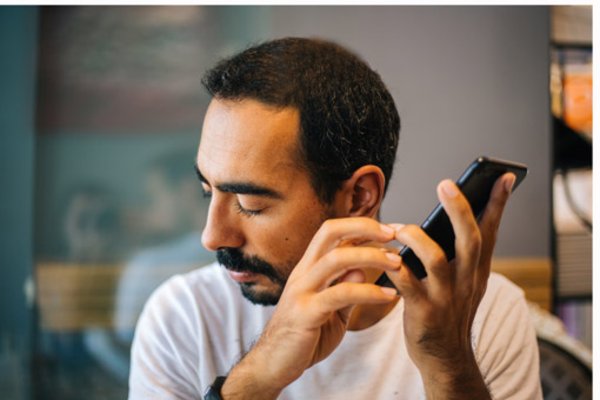 Photo of a man listening with closed eyes to his smartphone.