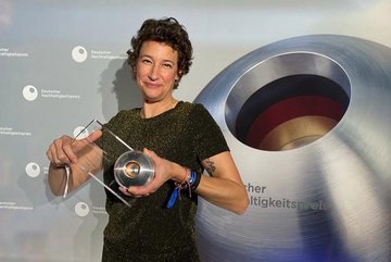 Foto von Svenja Weber, Geschäftsführerin des Dialoghaus Hamburg und von DSE, hält den Deutschne Nachhaltigkeitspreis in den Händen.