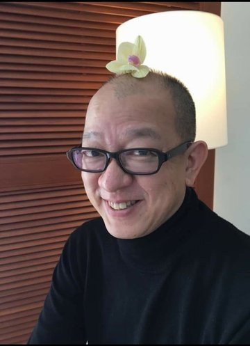 Portrait of a smiling Shinsuke with a flower on the top of his head.