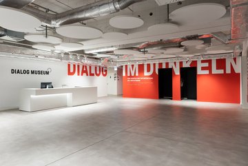 Foto des neuen Foyers des Dialaogmuseums, ein geräumiger, in Orange und Weiß gehaltener Raum.